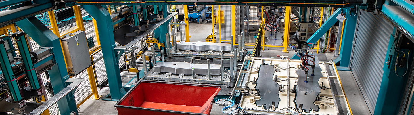Blick in eine Produktionsstätte, in der auf einer Maschinenstraße Autoteile aus Metall gefertigt werden.