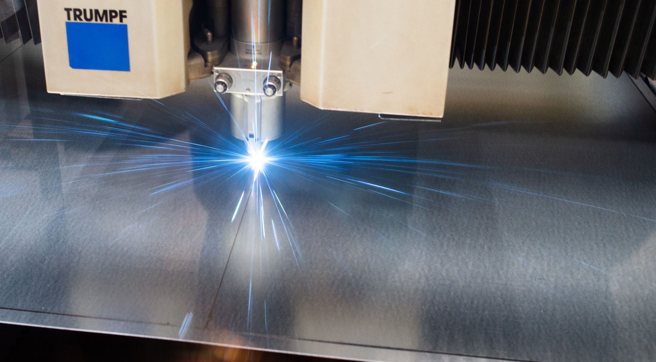 Dieses Bild zeigt einen Laser, der auf eine Metallplatte gerichtet ist und blau leuchtet.